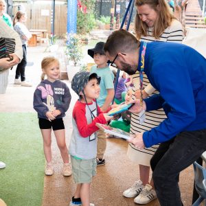 Learning Links Preschool child presenting painting to Officeworks team member