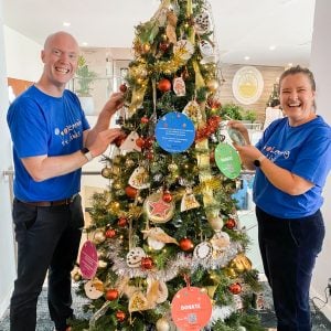 Two Learning Links staff members smiling while decorating Christmas tree at Cronulla RSL