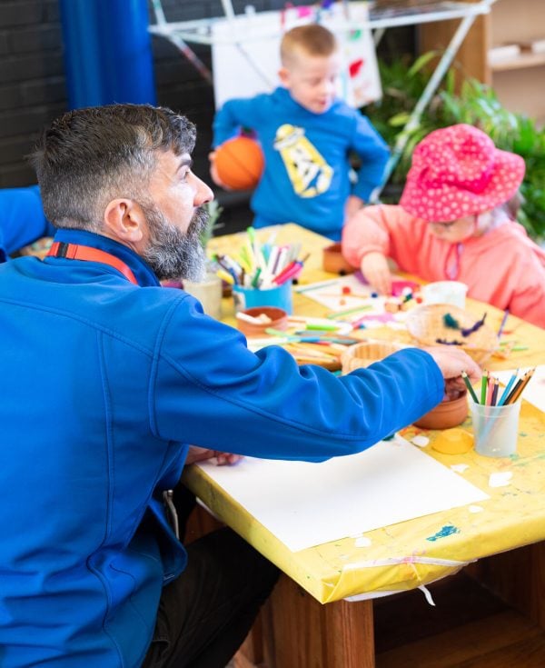 Officeworks staff sitting at table doing craft with Learning Links Preschool children