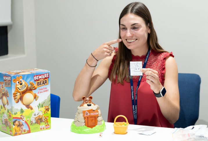 Speech pathologist holding up flash card with picture of sandcastle while pointing to mouth