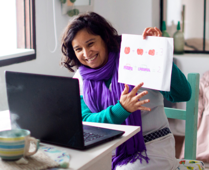 Teacher holding up paper with different shapes to count for online initial screener